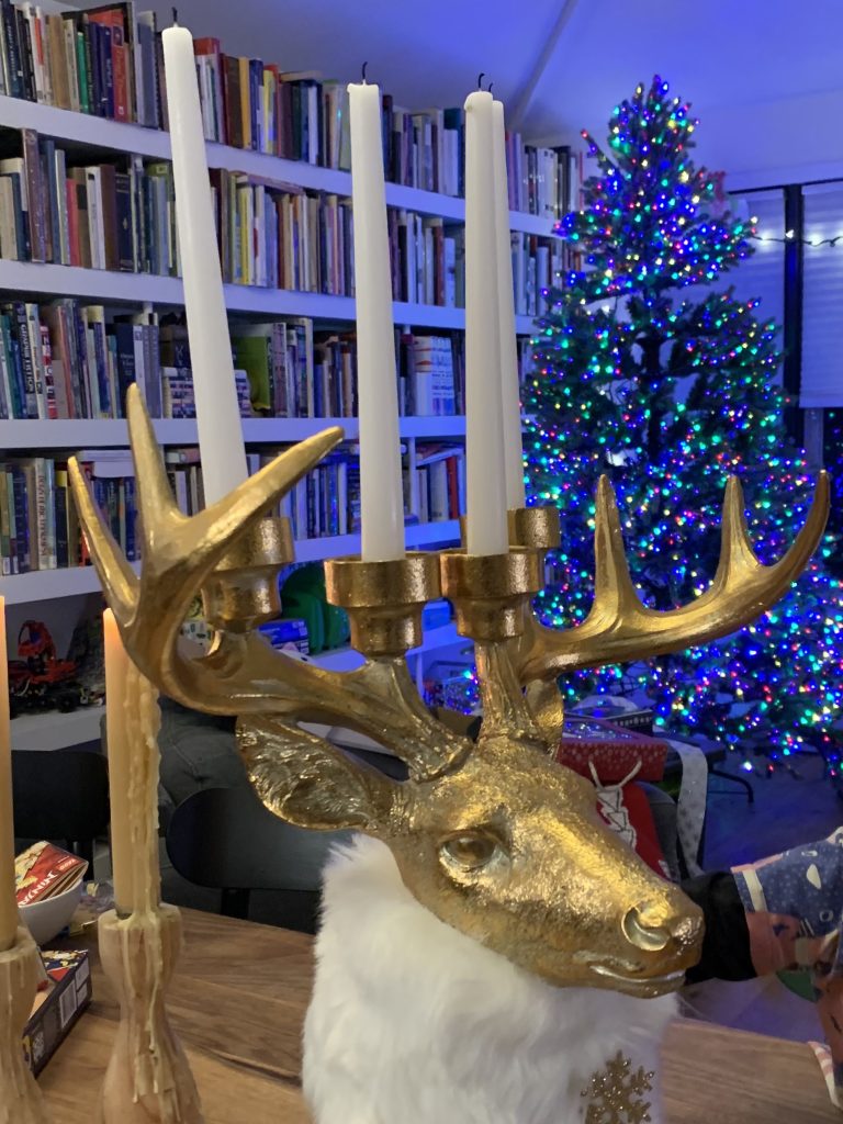 A golden reindeer head candelabra, RGB Xmas tree in the background. 